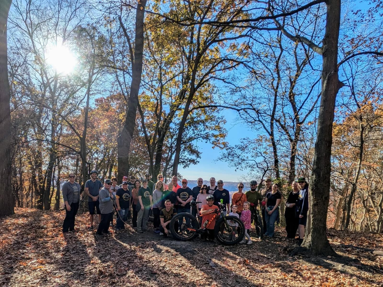 Friends of Norwin Trails volunteers gathered together on a wooded ridge trail on a sunny autumn day